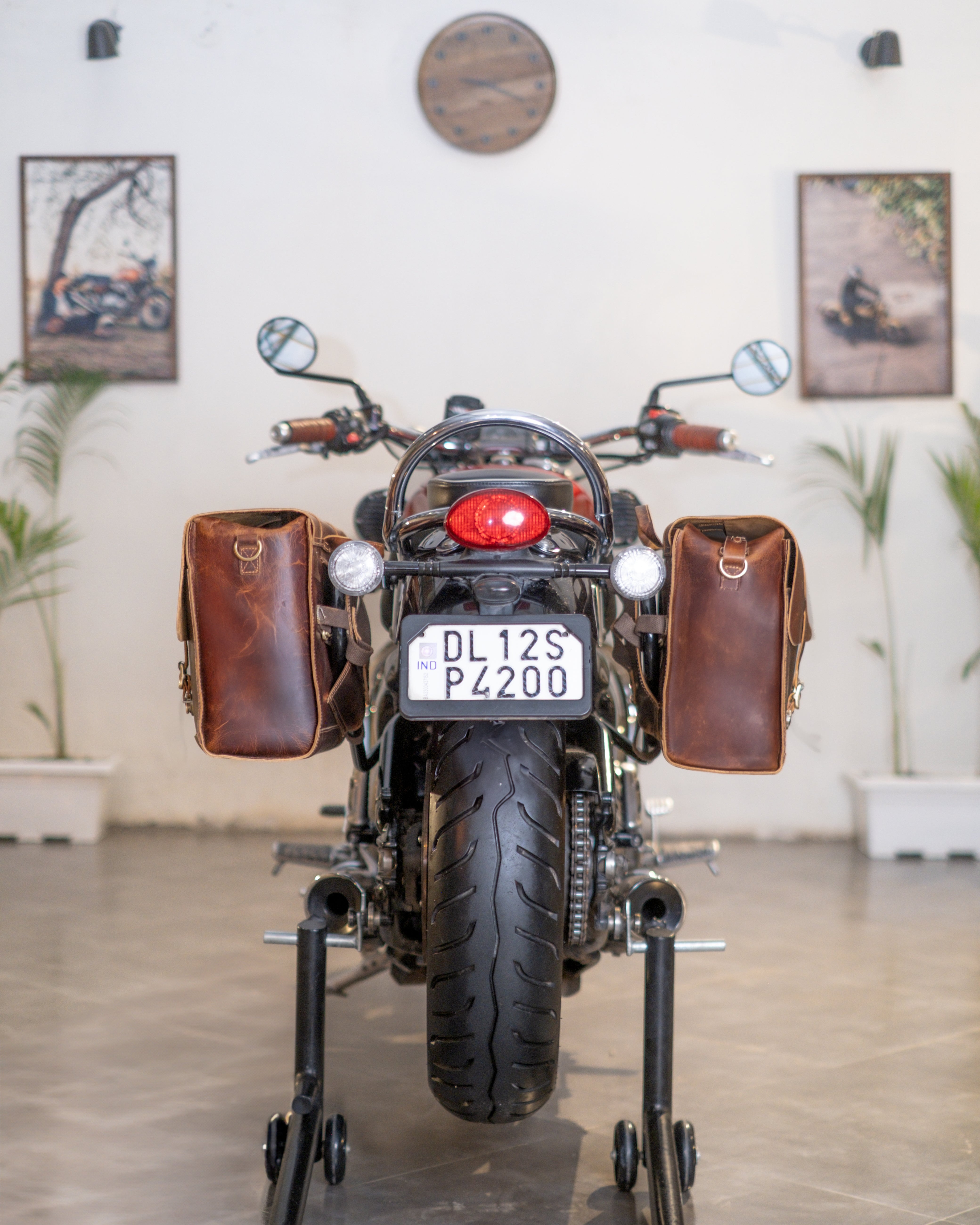 Motorcycle with brown leather saddlebags on a stand indoors.