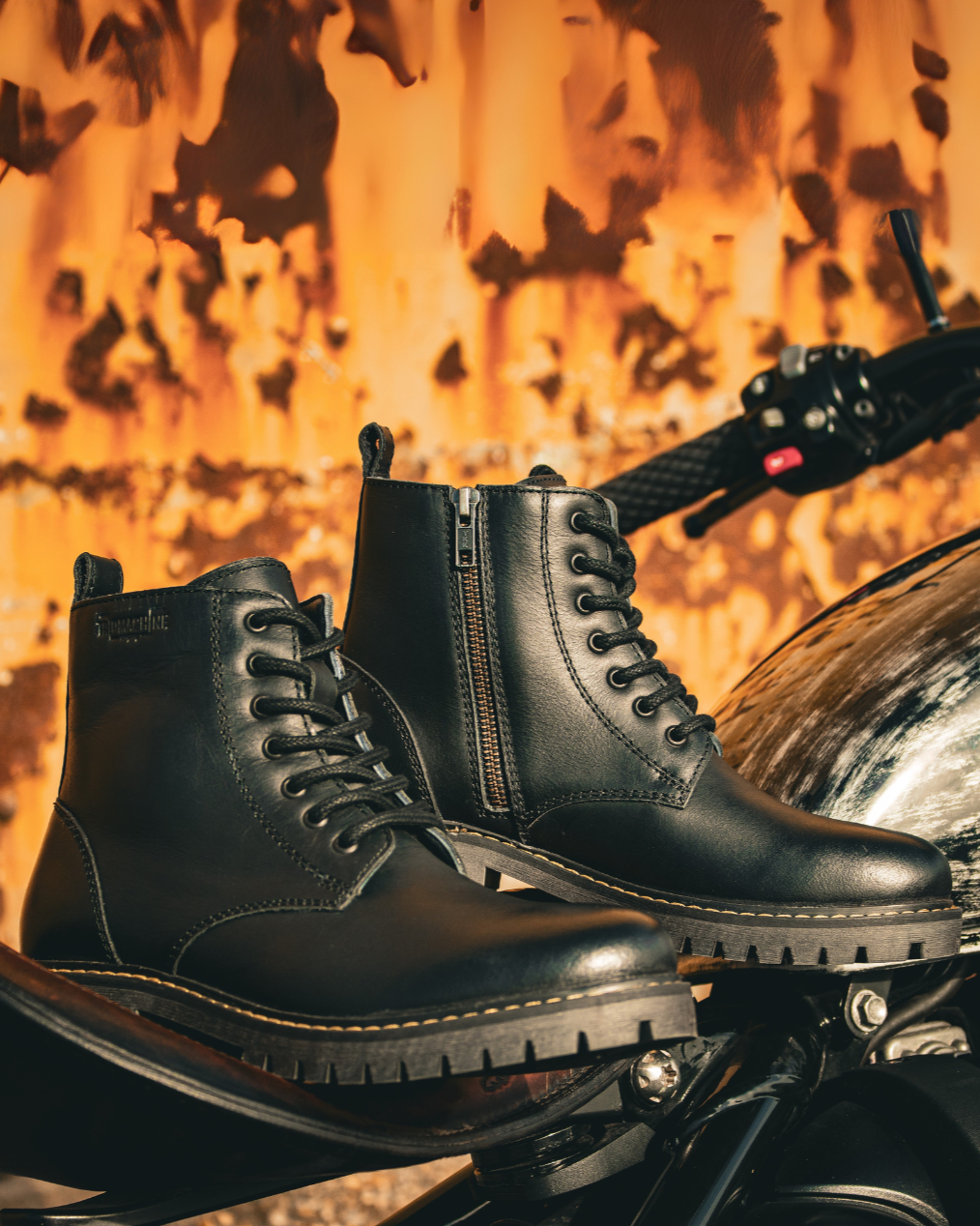 Black leather boots on a motorcycle with a fiery background
