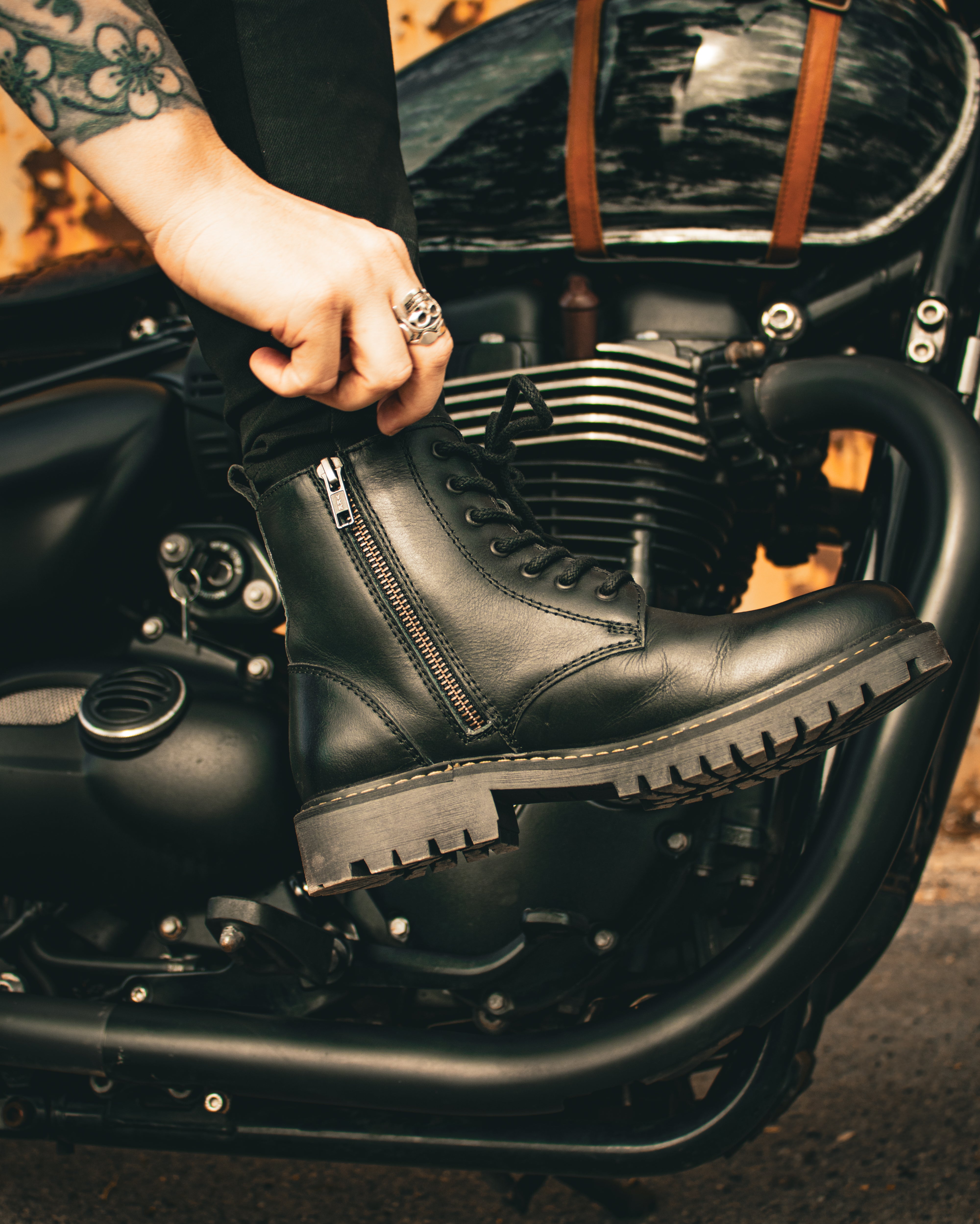 Person wearing black leather boots on a motorcycle with a blurred background