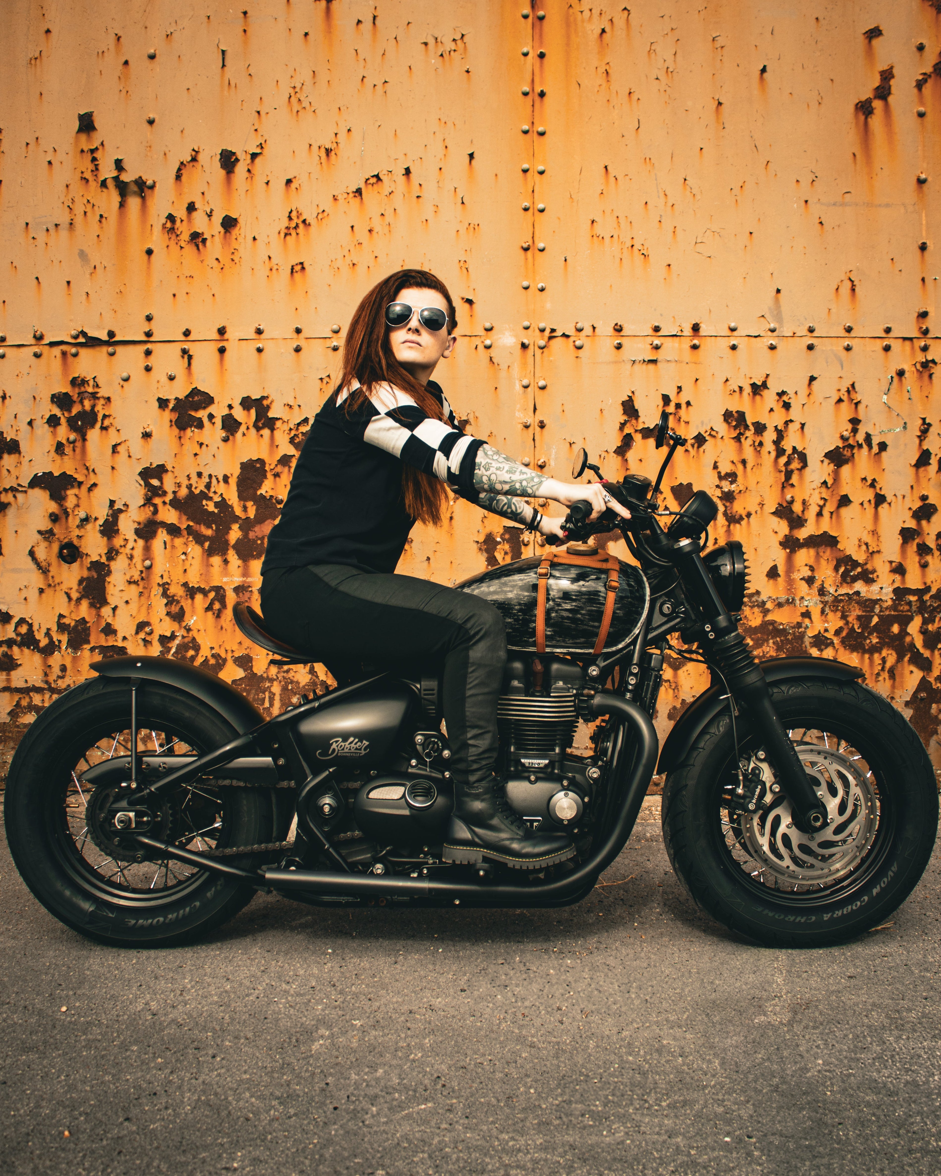 Person sitting on a motorcycle against a rusty wall