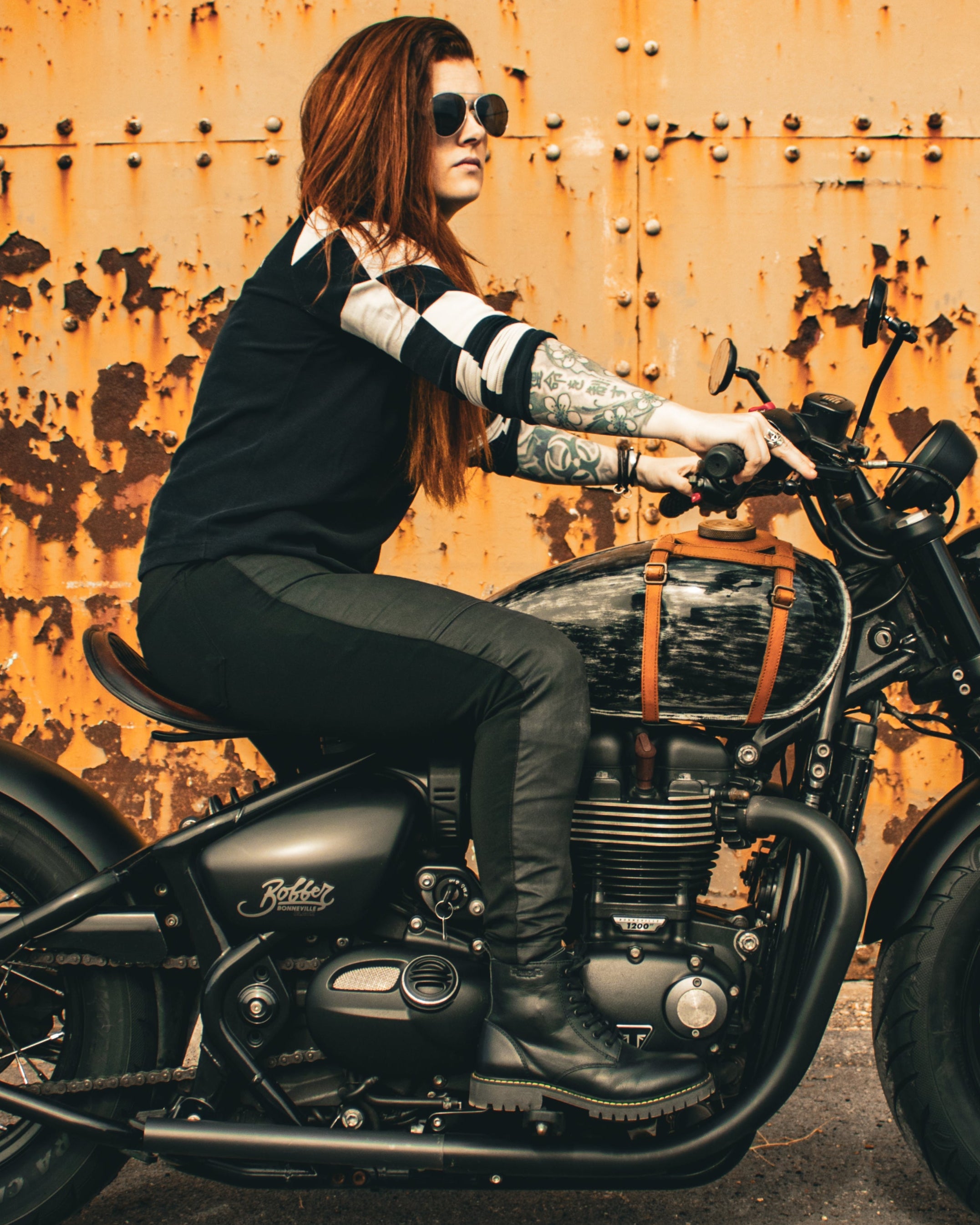 Person sitting on a motorcycle in front of a rusty wall
