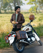 Man standing next to a motorcycle with leather bags in a natural setting
