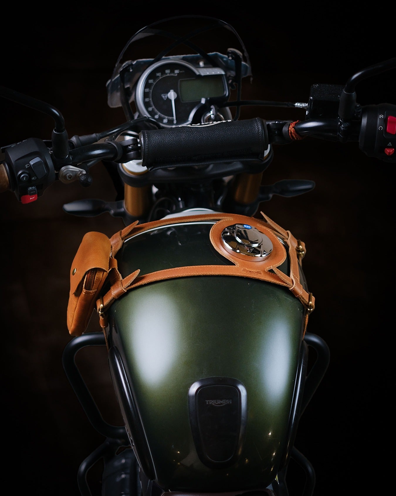 Close-up of a motorcycle's handlebar and dashboard with a dark background