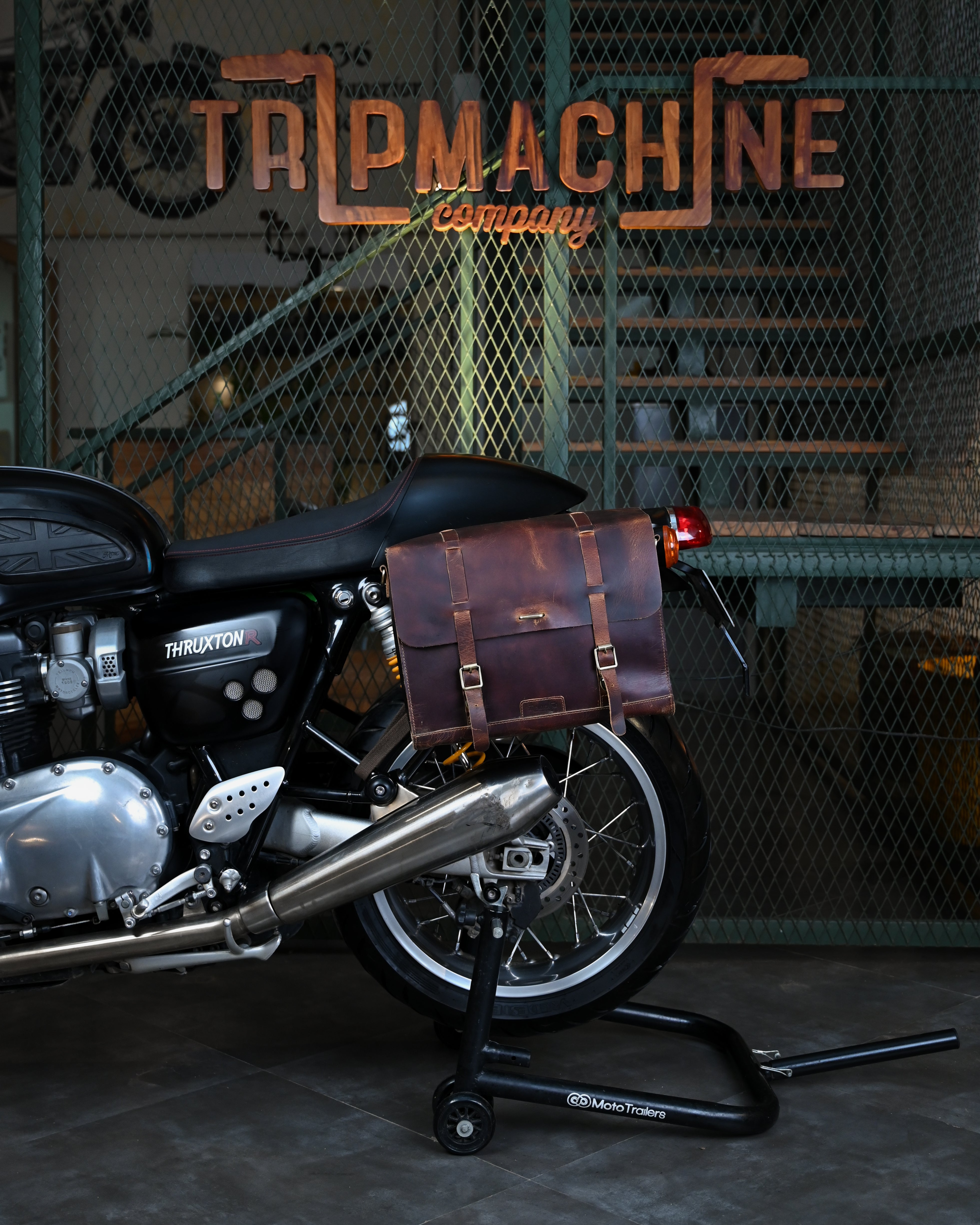 Motorcycle with leather saddlebags in a workshop setting, featuring 'TRM MACHINE' branding.
